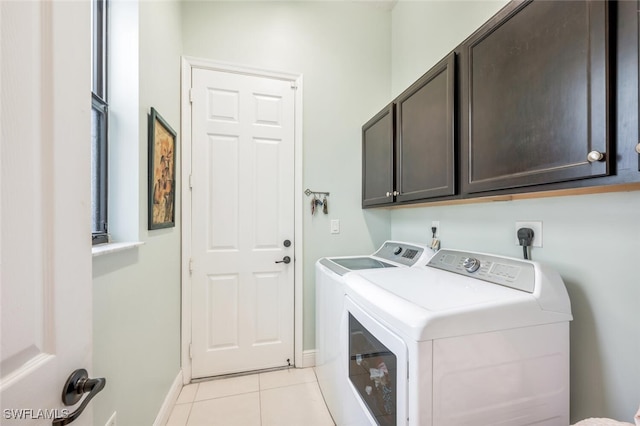 laundry area featuring washer and clothes dryer, light tile patterned floors, and cabinets