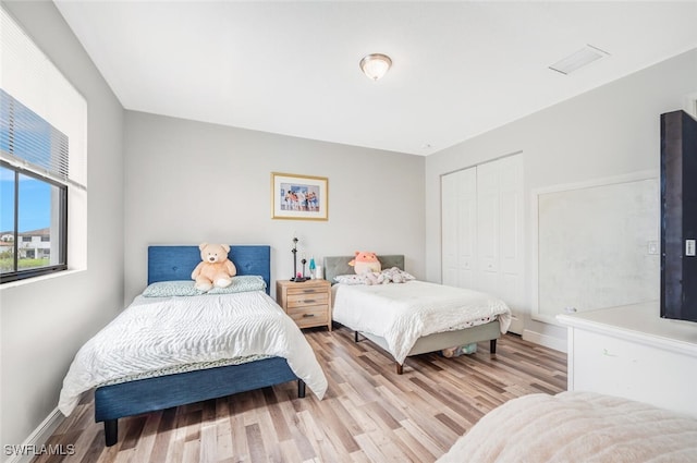 bedroom with light wood-type flooring and a closet