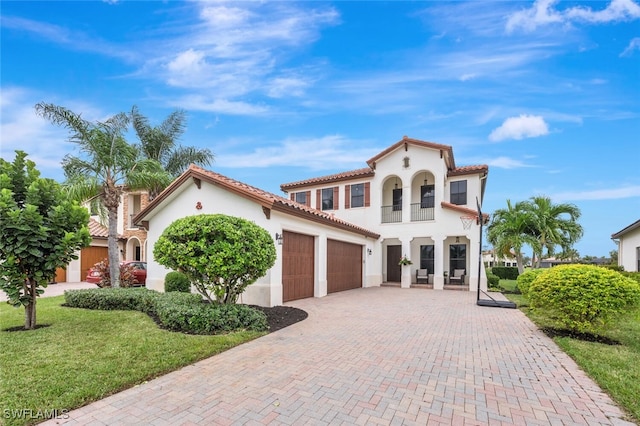 mediterranean / spanish home with a balcony, a front yard, and a garage