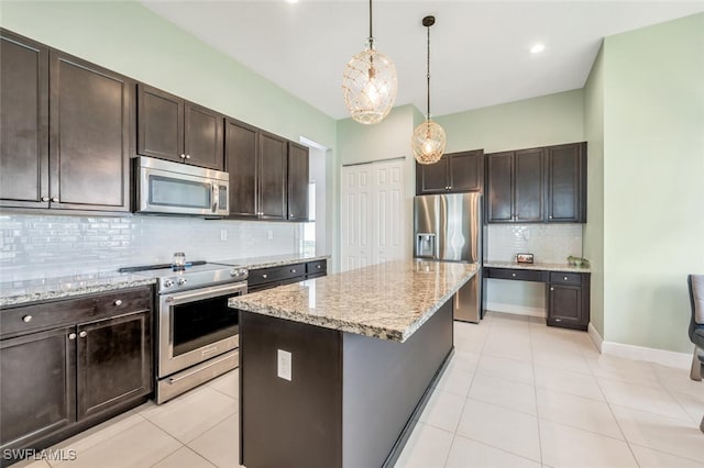 kitchen with dark brown cabinets, backsplash, appliances with stainless steel finishes, a kitchen island, and pendant lighting