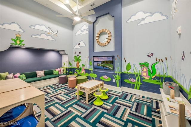 recreation room featuring ceiling fan, carpet, and a high ceiling