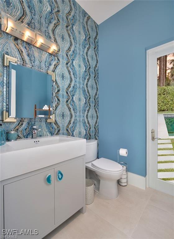 581 Myrtle Rd, Naples, FL 34108 - bathroom with vanity, tile patterned flooring, plenty of natural light, lofted ceiling, and wallpapered walls