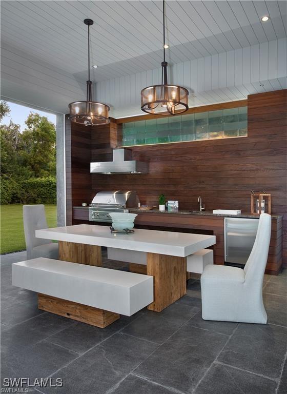 dining area featuring a high ceiling, wooden walls, and sink