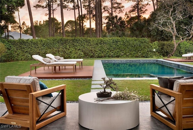 pool at dusk with a lawn and a wooden deck