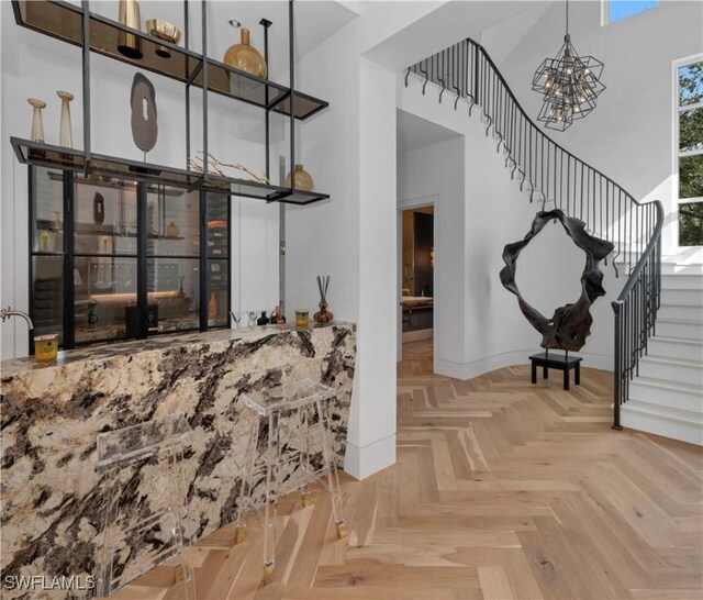 581 Myrtle Rd, Naples, FL 34108 - bar featuring a high ceiling, stairway, and a chandelier