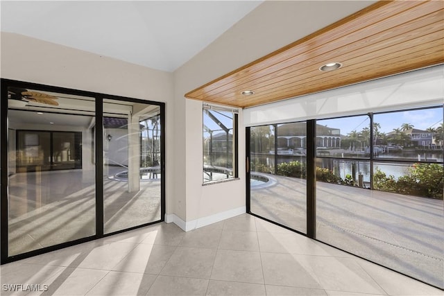 unfurnished room with a water view, light tile patterned floors, and wooden ceiling