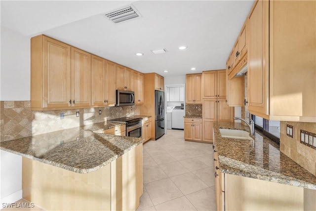 kitchen with dark stone counters, sink, a kitchen bar, kitchen peninsula, and stainless steel appliances