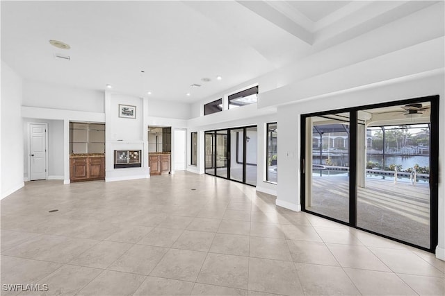 unfurnished living room with light tile patterned floors, a towering ceiling, and ceiling fan