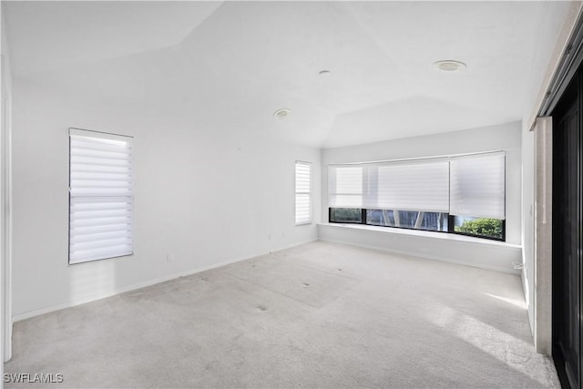 unfurnished living room featuring light colored carpet and vaulted ceiling