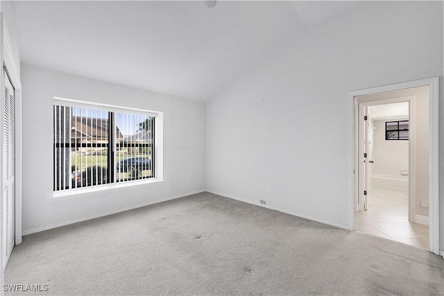 empty room with light colored carpet and lofted ceiling