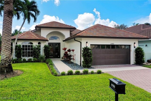 mediterranean / spanish home with a front yard, a garage, and french doors