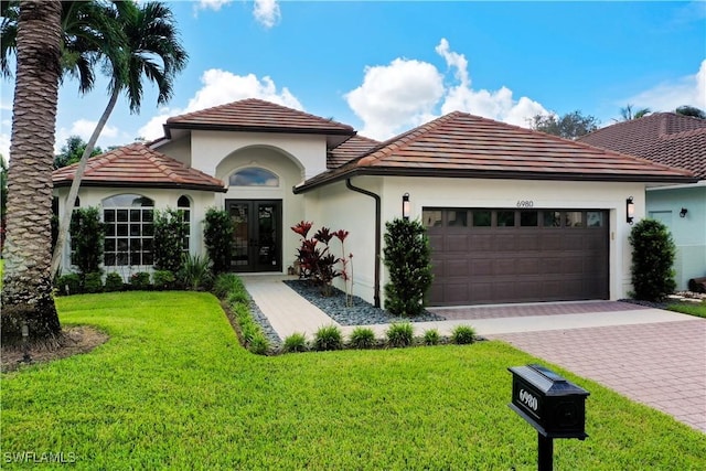 mediterranean / spanish house with a front lawn, a garage, and french doors