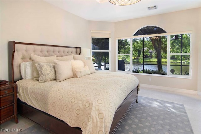 bedroom with a water view and multiple windows