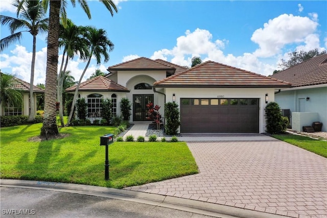 mediterranean / spanish house featuring a garage, a front lawn, and french doors