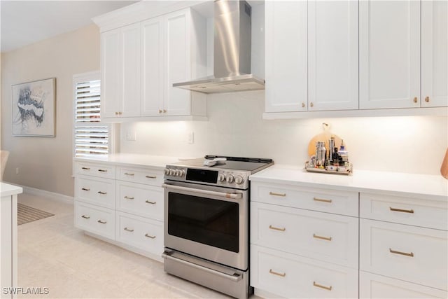 kitchen with wall chimney range hood, stainless steel range with electric cooktop, and white cabinetry