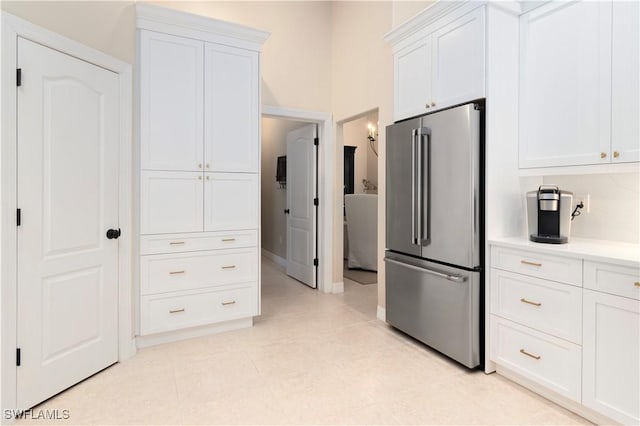 kitchen with light tile patterned floors, white cabinetry, and stainless steel fridge