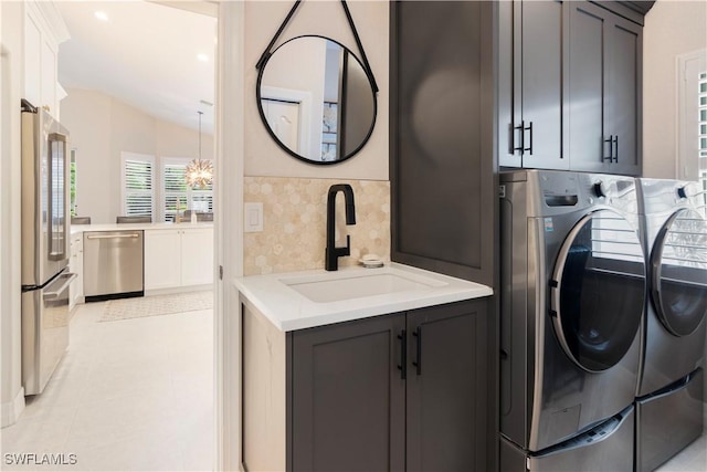 laundry area with separate washer and dryer, cabinets, an inviting chandelier, sink, and light tile patterned floors