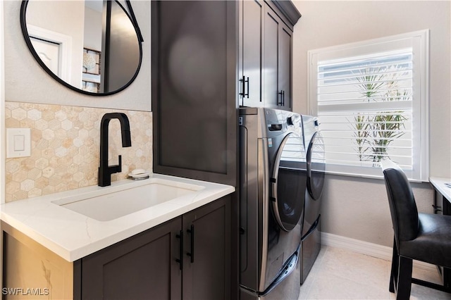 laundry room with light tile patterned floors, washing machine and dryer, sink, and cabinets