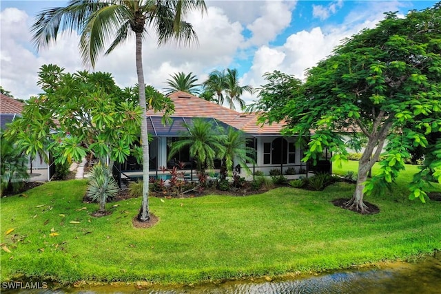 rear view of house with a lanai and a lawn