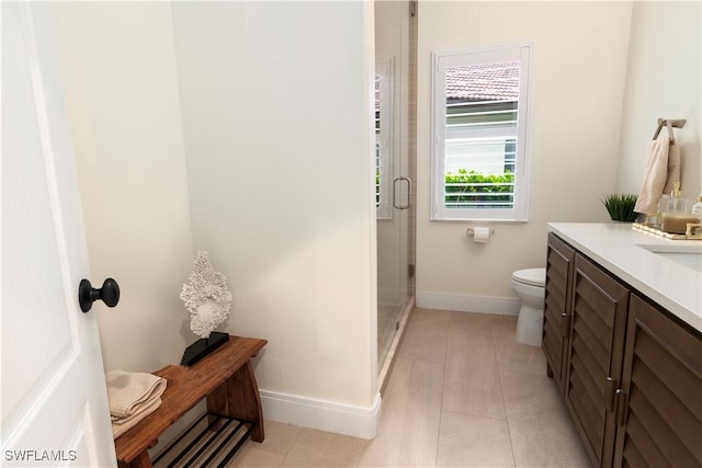 bathroom featuring toilet, vanity, tile patterned floors, and a shower with door