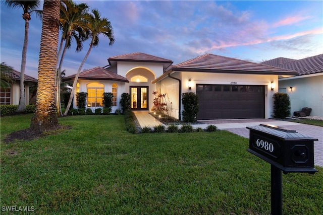 view of front of property featuring a garage, a yard, and french doors