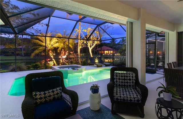 pool at dusk featuring a lanai, a patio area, and an in ground hot tub