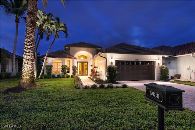 view of front of home with a front lawn, a garage, and french doors