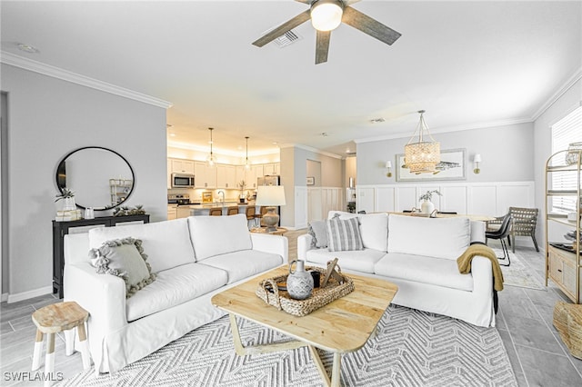 living room featuring ceiling fan with notable chandelier, ornamental molding, and sink