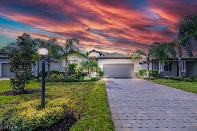 ranch-style home featuring a garage and a lawn