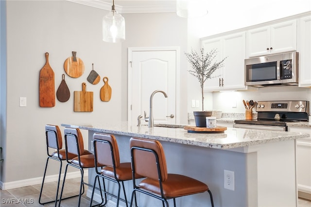 kitchen with crown molding, a center island with sink, hanging light fixtures, appliances with stainless steel finishes, and white cabinetry