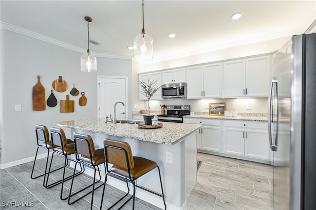 kitchen with pendant lighting, sink, a center island with sink, white cabinetry, and appliances with stainless steel finishes