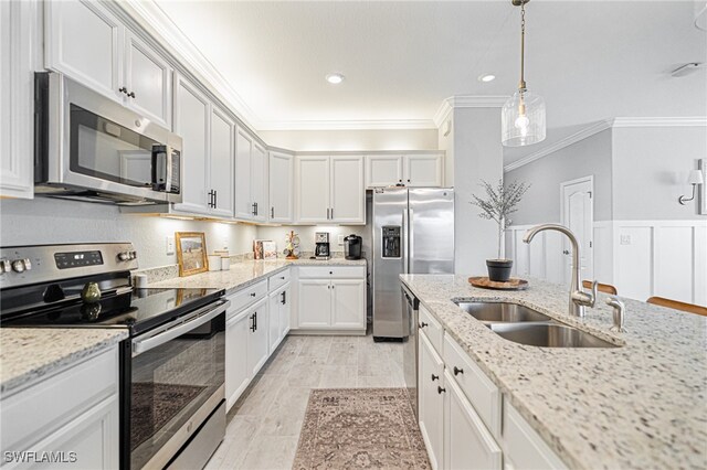 kitchen with light stone countertops, white cabinets, sink, ornamental molding, and appliances with stainless steel finishes