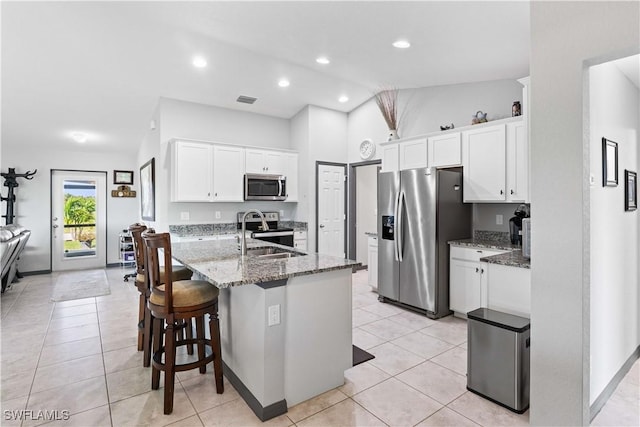 kitchen featuring light tile patterned floors, white cabinetry, appliances with stainless steel finishes, stone countertops, and sink