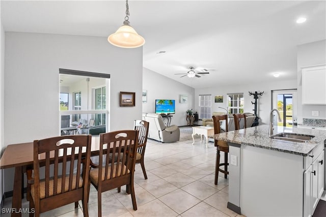 tiled dining space featuring ceiling fan, vaulted ceiling, and sink