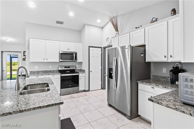 kitchen with white cabinets, appliances with stainless steel finishes, sink, and stone countertops