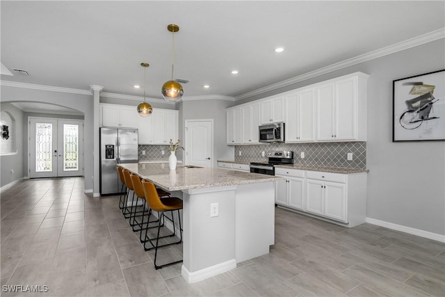19644 The Place Blvd, Estero, FL 33928 - kitchen with appliances with stainless steel finishes, arched walkways, a kitchen breakfast bar, white cabinets, and a kitchen island with sink
