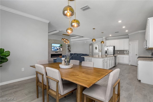 dining room featuring a large fireplace, visible vents, crown molding, and baseboards