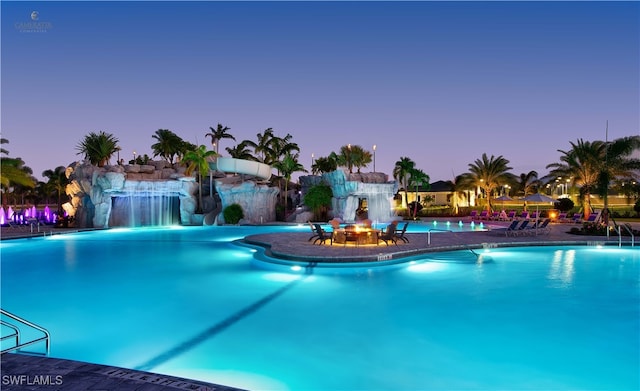 pool at dusk featuring a patio area and pool water feature