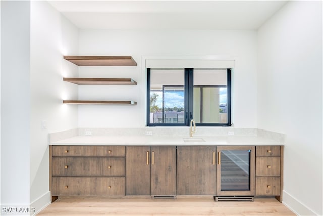 bar featuring beverage cooler, light hardwood / wood-style flooring, and sink