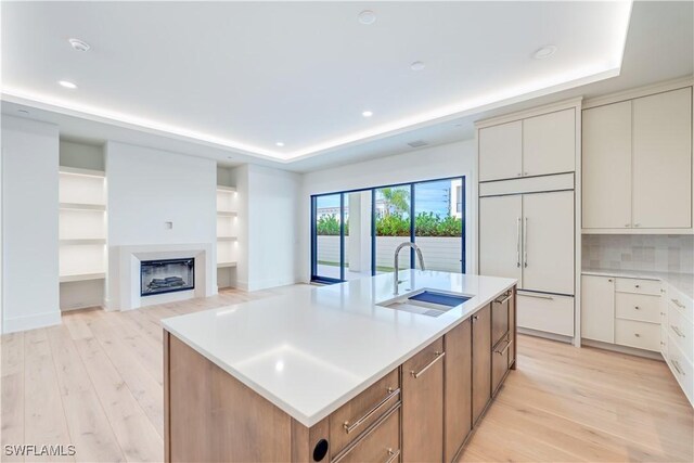 kitchen featuring light hardwood / wood-style flooring, paneled built in refrigerator, sink, and a spacious island