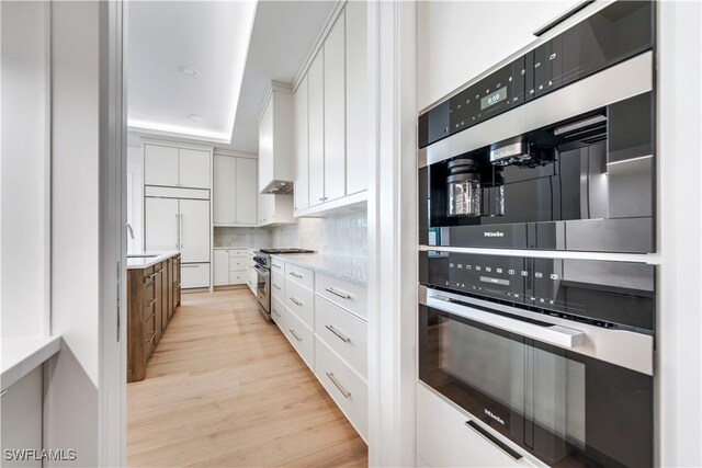 kitchen with backsplash, premium appliances, sink, and white cabinets