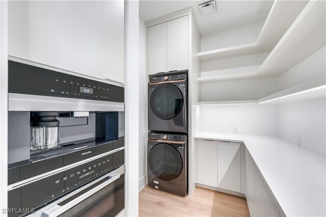 washroom with stacked washer and dryer and light wood-type flooring