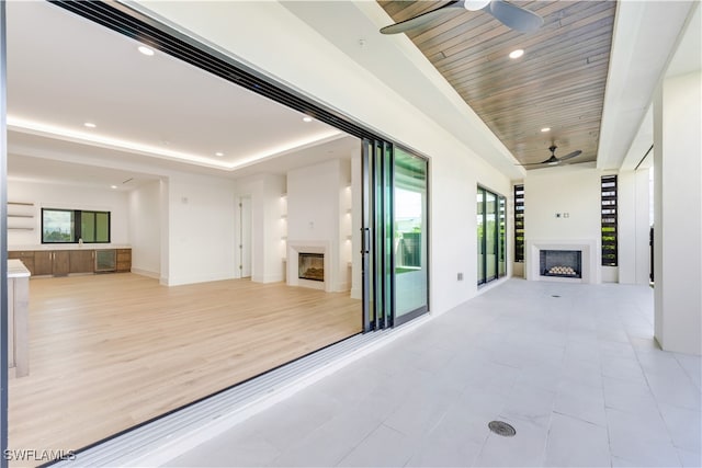 corridor with a raised ceiling, wood ceiling, and light hardwood / wood-style flooring