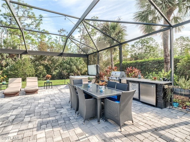 view of patio with a lanai, grilling area, and an outdoor kitchen