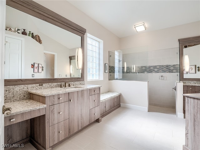 bathroom featuring vanity, lofted ceiling, tiled shower, and tile patterned flooring