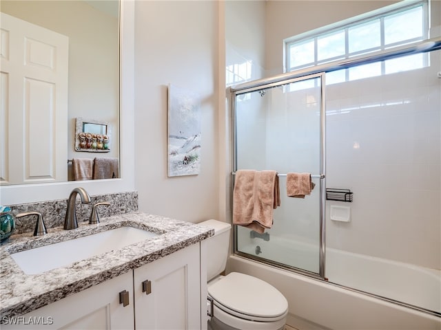 full bathroom with vanity, enclosed tub / shower combo, and toilet