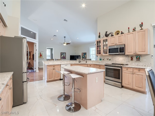 kitchen featuring a kitchen island, a breakfast bar area, kitchen peninsula, stainless steel appliances, and ceiling fan