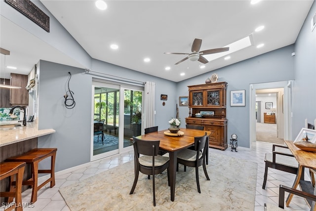 dining space with lofted ceiling with skylight, sink, and ceiling fan