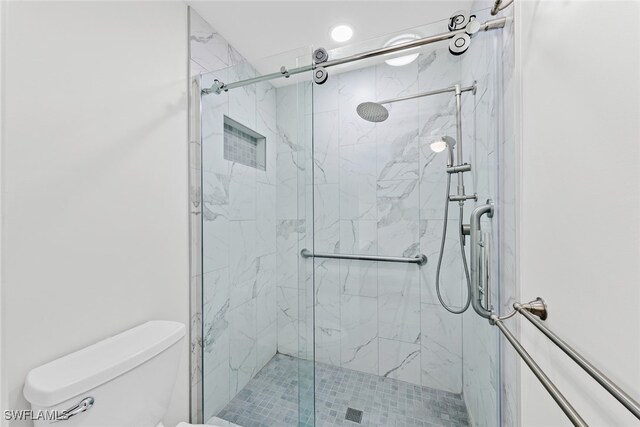 bathroom featuring toilet and a shower with door