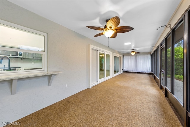 unfurnished sunroom with ceiling fan, sink, and plenty of natural light